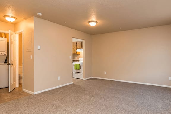 A room with a carpeted floor and a white refrigerator.