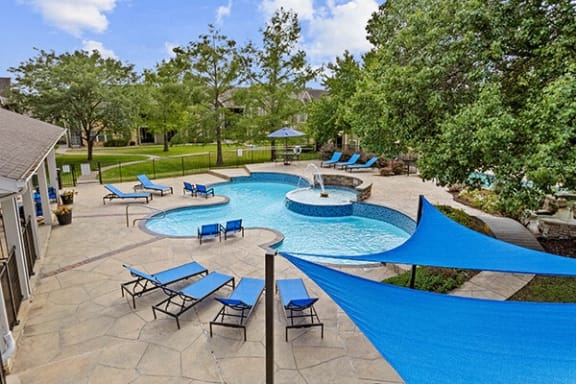 a resort style pool with blue umbrellas and chairs