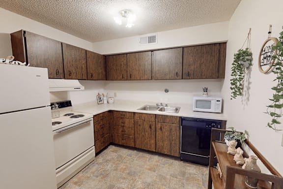 A kitchen with a white refrigerator, black oven, and wooden cabinets.