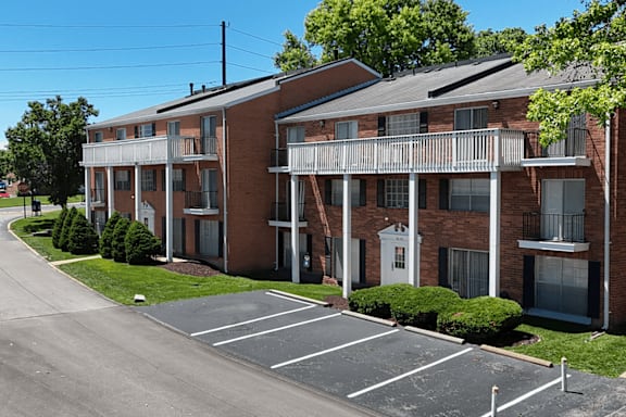 A parking lot in front of a brick apartment building.