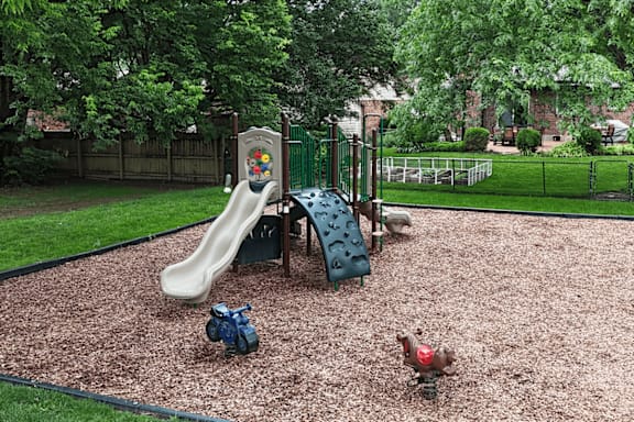 A playground with a slide, a seesaw, and a ball.