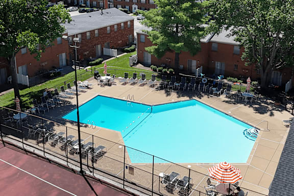 A pool surrounded by a black fence and chairs.
