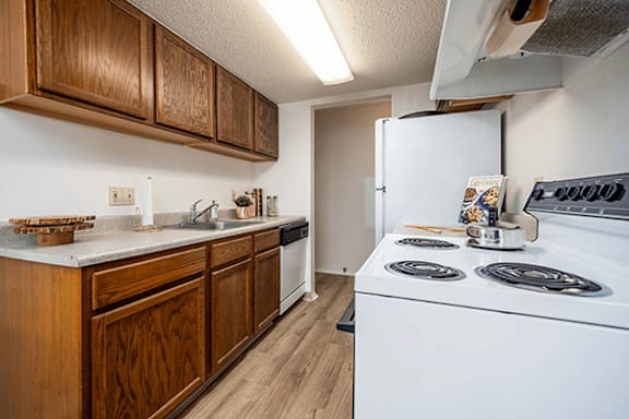 A kitchen with a white stove top oven and wooden cabinets.
