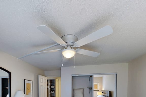 A white ceiling fan with a light hanging from the ceiling in a room.