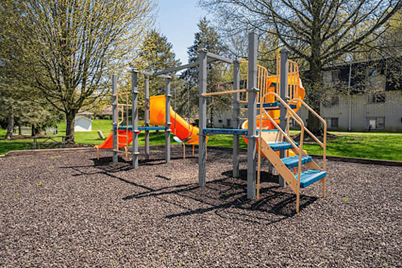 A playground with a yellow slide and a blue bench.