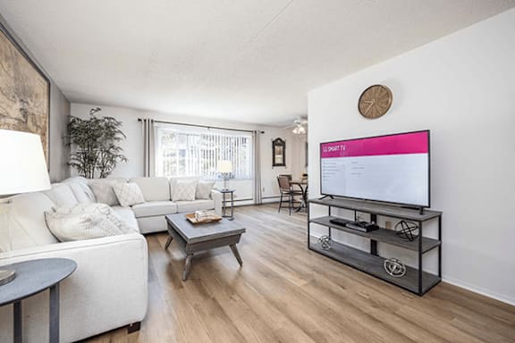 A living room with a white couch, a coffee table, and a flat screen TV.