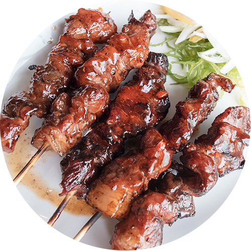 A plate of grilled meat skewers with a side of shredded cabbage.