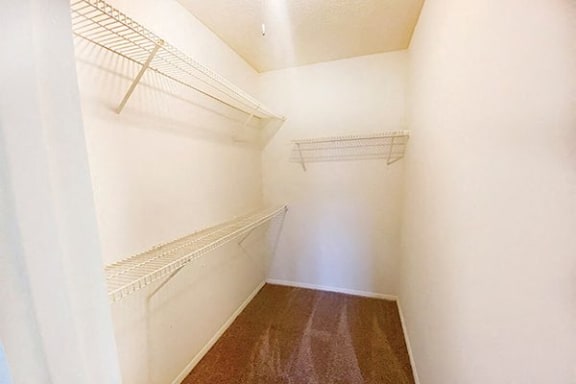 a walk in closet with white walls and shelves
