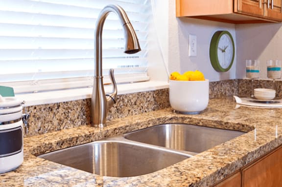 a kitchen sink with a chrome faucet on a granite counter top