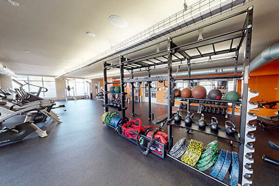 A gym with a variety of equipment including treadmills, weights, and resistance bands.