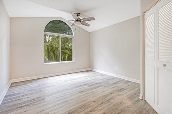 A room with a window and a fan on the ceiling.