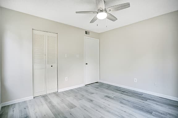 A room with a ceiling fan and two doors.