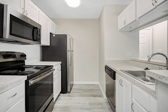 A kitchen with black appliances and white cabinets.