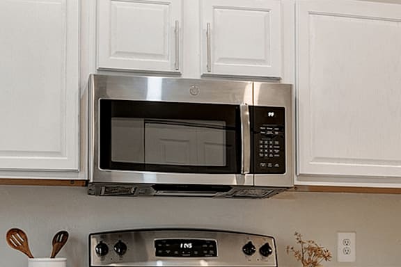 A silver microwave oven is installed above a stove.