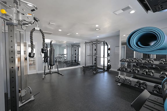 A gym with a variety of equipment including a treadmill, weights, and a yoga mat.