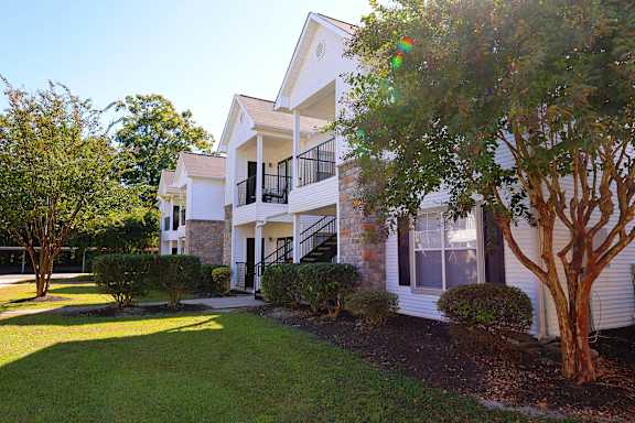 A white two-story house with a balcony on the second floor.
