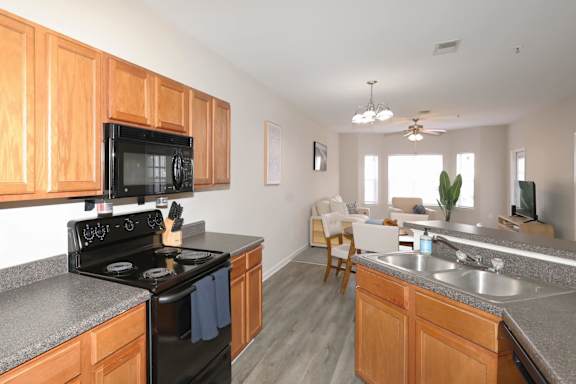A kitchen with a black stove and wooden cabinets.