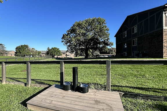 A wooden platform with two black objects on it in front of a grassy field.