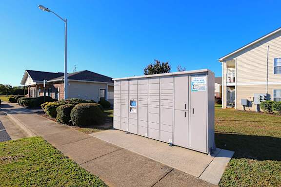 A large grey storage unit is situated on a sidewalk in front of a residential building.