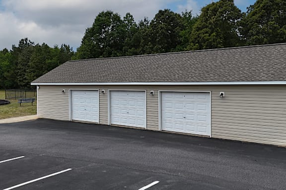 A building with three garage doors in front of a tree.