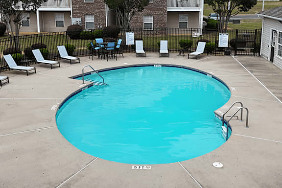A small pool surrounded by chairs and tables.