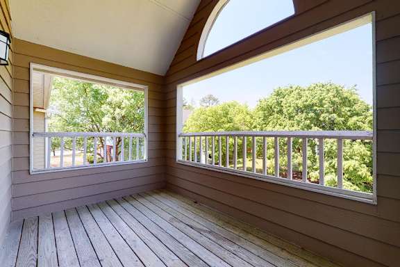 A balcony with a railing and a view of trees.