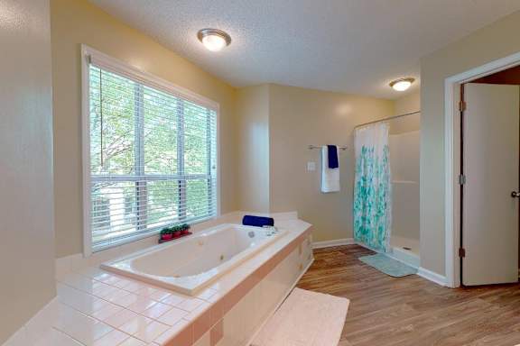 A bathroom with a large tub and a window with blinds.