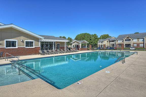 A large swimming pool in front of a building with a clear blue sky above.