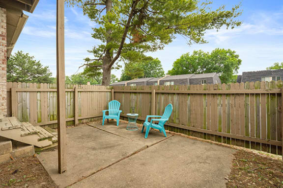 a patio with two chairs and a table in front of a fence