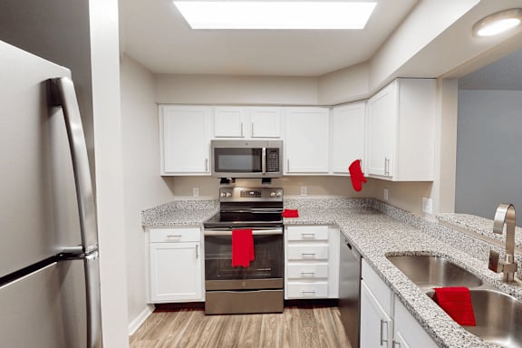 A kitchen with white cabinets and a black refrigerator.