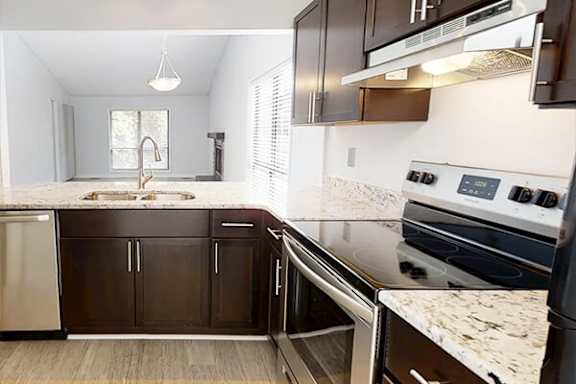 A modern kitchen with dark brown cabinets and stainless steel appliances.