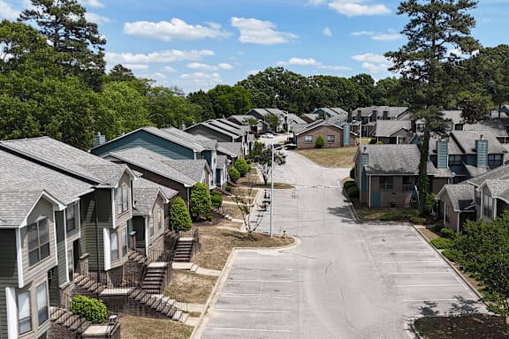 A residential street with lots of parking with houses on both sides and a clear sky above.