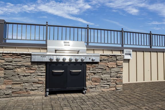a barbecue grill with a stone wall and a blue sky in the background