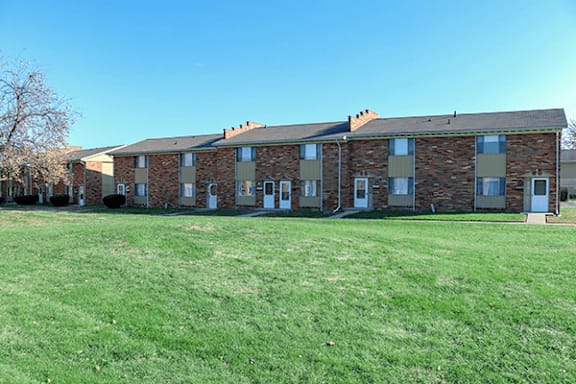 A large grassy field in front of a brick building.