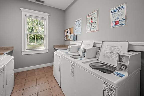 A laundry room with washers and dryers and a window.