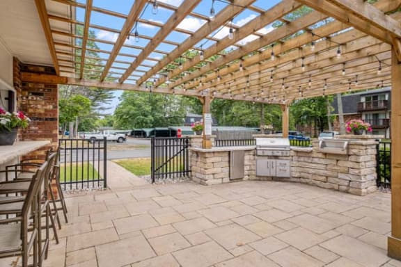 a patio with a pergola and a grill
