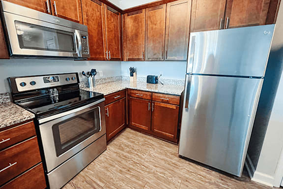 A kitchen with a stainless steel refrigerator, microwave, oven, and cabinets.