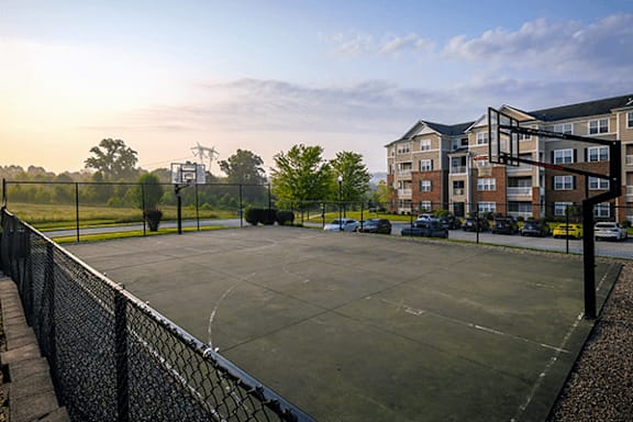 A tennis court is surrounded by a black fence and is located in a residential area.