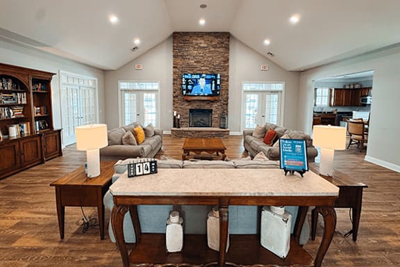 A living room with a stone fireplace and a large wooden table.