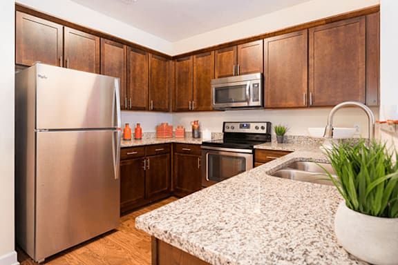 A kitchen with a stainless steel refrigerator, microwave, oven, and sink.