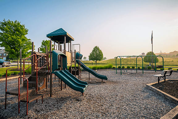 A playground with a green slide and a wooden structure.