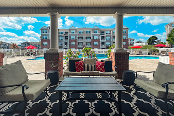 A patio with a table and chairs overlooking a pool.