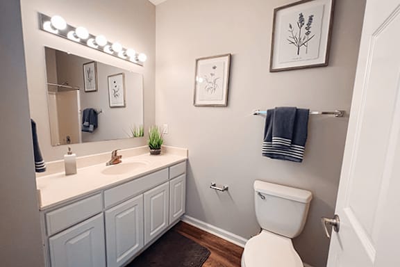 A white bathroom with a toilet, sink, mirror, and towel.