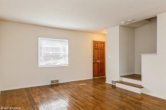 an empty living room with wood floors and a window