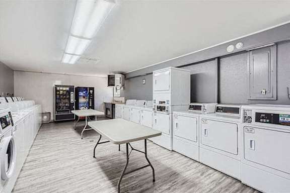 an empty laundry room with white appliances and tables