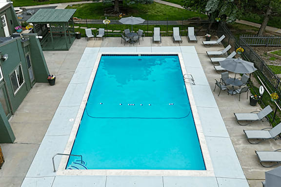 A rectangular pool with a sundeck around it with lounge chairs