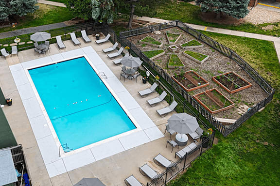 A pool surrounded by sundeck and a community garden nearby
