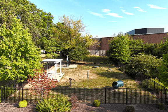 a yard with a fence and a garden with trees and a building