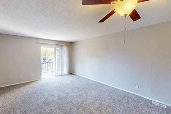 an empty living room with a ceiling fan