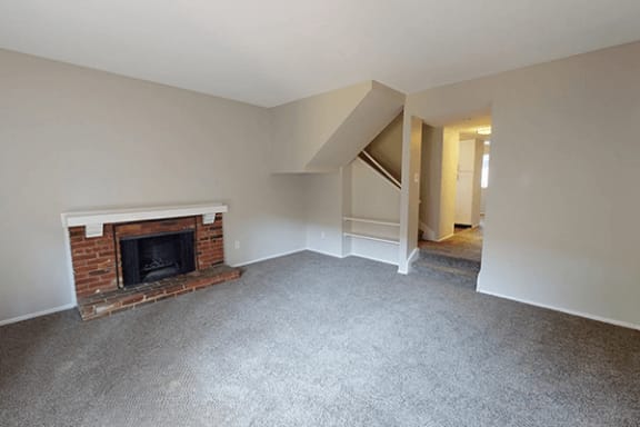 an empty living room with a brick fireplace